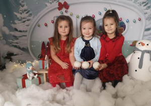 Laura, Marysia i Maja pozują do zdjęcia siedząc na ławeczce, wśród zimowo- świątecznej dekoracji.